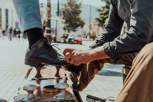 een oud Mens hand- polijsten en schilderij een zwart schoen Bij straat foto