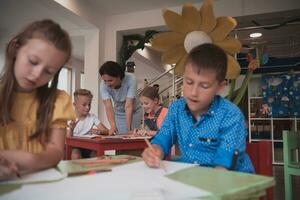 creatief kinderen gedurende een kunst klasse in een kinderopvang centrum of elementair school- klas tekening met vrouw docent. foto