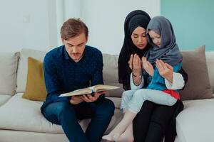 gelukkig moslim familie genieten van de heilig maand van Ramadan terwijl bidden en lezing de koran samen in een modern huis foto