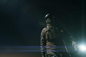 leger soldaat in gevecht uniformen met een aanval geweer, bord vervoerder en gevecht helm gaan Aan een gevaarlijk missie Aan een regenachtig nacht. foto