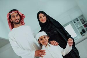 portret van jong gelukkig Arabisch moslim familie paar met zoon in traditioneel kleren uitgeven tijd samen gedurende de maand van Ramadan Bij huis foto