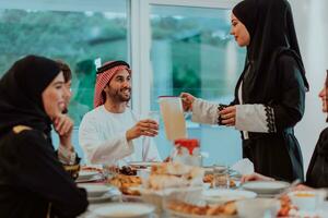 moslim familie hebben iftar avondeten drinken water naar breken feest. aan het eten traditioneel voedsel gedurende Ramadan feesten maand Bij huis. de Islamitisch halal aan het eten en drinken in modern huis foto