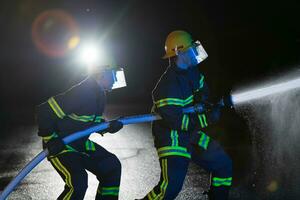 brandweerlieden gebruik een water slang naar elimineren een brand gevaar. team van brandweer in de gevaarlijk redden missie. foto