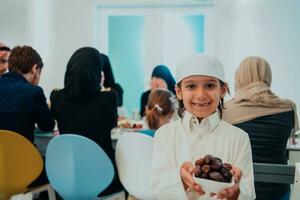 eid mubarak moslim familie hebben iftar avondeten weinig jongen Holding een bord vol van zoet datums naar breken feest. aan het eten traditioneel voedsel gedurende Ramadan feesten maand Bij huis. de Islamitisch halal aan het eten foto