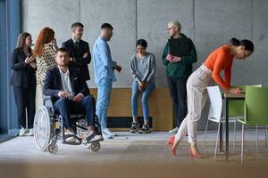 verschillend groep van bedrijf mensen, inclusief een zakenman in een rolstoel in een modern kantoor foto