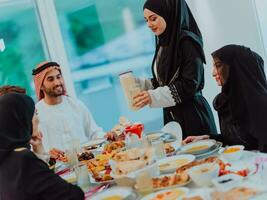 eid mubarak moslim familie hebben iftar avondeten drinken water naar breken feest. aan het eten traditioneel voedsel gedurende Ramadan feesten maand Bij huis. de Islamitisch halal aan het eten en drinken foto