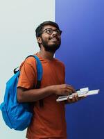 Indisch leerling met blauw rugzak, bril en notitieboekje poseren Aan de paarsgrijs achtergrond. de concept van onderwijs en scholing. tijd naar Gaan terug naar school- foto