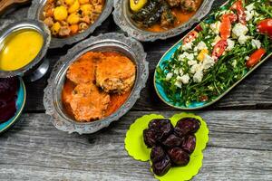 eid mubarak traditioneel Ramadan iftar diner. geassorteerd smakelijk voedsel in authentiek rustiek gerechten Aan houten blauw achtergrond. Turks Bosnisch voedsel vlees kebab, pita, sarma, klepe, zogan dolma. foto