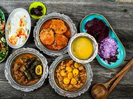 eid mubarak traditioneel Ramadan iftar diner. geassorteerd smakelijk voedsel in authentiek rustiek gerechten Aan houten blauw achtergrond. Turks Bosnisch voedsel vlees kebab, pita, sarma, klepe, zogan dolma. foto