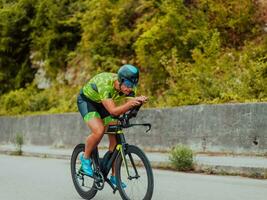 vol lengte portret van een actief triatleet in sportkleding en met een beschermend helm rijden een fiets. selectief focus foto