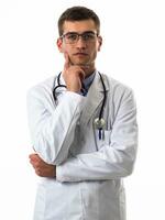 portret van held in wit jas. vrolijk glimlachen jong dokter met stethoscoop in medisch ziekenhuis staand tegen wit achtergrond. coronavirus covid-19 Gevaar alarm foto