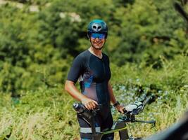 dichtbij omhoog foto van een actief triatleet in sportkleding en met een beschermend helm rijden een fiets. selectief focus