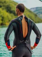 atleet zetten Aan een zwemmen pak en voorbereidingen treffen voor triatlon zwemmen en opleiding in de rivier- omringd door natuurlijk groen foto