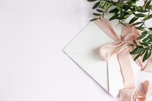 envelop op een wit-roze achtergrond met perzik zijden lint en roze foto