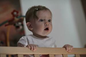 schattig weinig een jaar oud baby en maken eerste stappen in bed foto