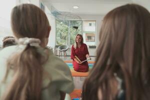 lezing tijd in een elementair school- of kleuterschool, een leraar leest een boek naar kinderen in een elementair school- of kleuterschool. de concept van peuter onderwijs. selectief focus foto