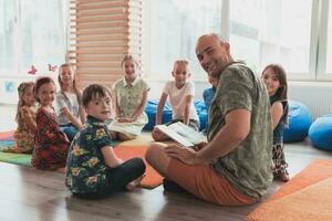 lezing tijd in elementair school- of kleuterschool, leraar lezing een boek naar kinderen in elementair school- of kindergaden. selectief focus foto