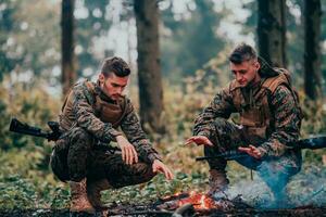 twee uitgeput soldaten zittend door de brand na een moe en zwaar oorlog strijd foto