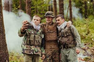 team van soldaten en terrorist nemen selfie met smartphone in de Woud foto