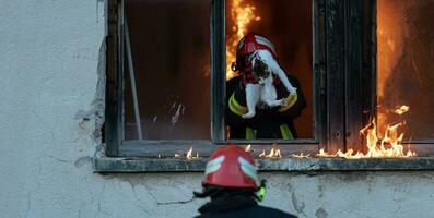 brandweerman held draag- baby meisje uit van brandend gebouw Oppervlakte van brand incident. redden mensen van gevaarlijk plaats foto