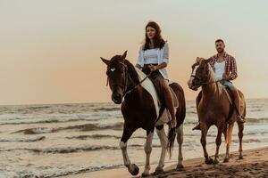 een liefhebbend paar in zomer kleren rijden een paard Aan een zanderig strand Bij zonsondergang. zee en zonsondergang in de achtergrond. selectief focus foto