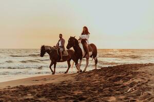 een liefhebbend paar in zomer kleren rijden een paard Aan een zanderig strand Bij zonsondergang. zee en zonsondergang in de achtergrond. selectief focus foto