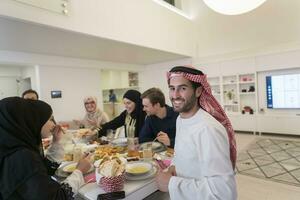 jong Arabisch Mens hebben iftar avondeten met moslim familie aan het eten traditioneel voedsel gedurende Ramadan feesten maand Bij huis. de Islamitisch halal aan het eten en drinken Islamitisch familie foto