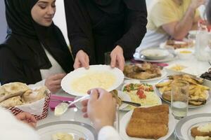 eid mubarak moslim familie hebben iftar avondeten drinken water naar breken feest. aan het eten traditioneel voedsel gedurende Ramadan feesten maand Bij huis. de Islamitisch halal aan het eten en drinken Bij modern western isla foto