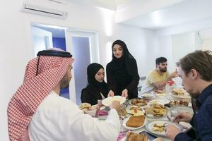 eid mubarak moslim familie hebben iftar avondeten drinken water naar breken feest. aan het eten traditioneel voedsel gedurende Ramadan feesten maand Bij huis. de Islamitisch halal aan het eten en drinken Bij modern western isla foto