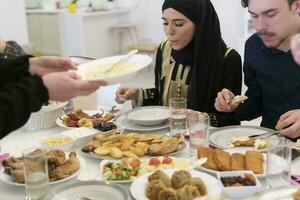 eid mubarak moslim familie hebben iftar avondeten drinken water naar breken feest. aan het eten traditioneel voedsel gedurende Ramadan feesten maand Bij huis. de Islamitisch halal aan het eten en drinken Bij modern western isla foto