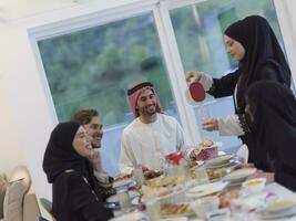 eid mubarak moslim familie hebben iftar avondeten drinken water naar breken feest. aan het eten traditioneel voedsel gedurende Ramadan feesten maand Bij huis. de Islamitisch halal aan het eten en drinken Bij modern western isla foto