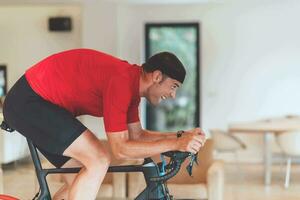 een Mens rijden een triatlon fiets Aan een machine simulatie in een modern leven kamer. opleiding gedurende pandemisch conditie. foto