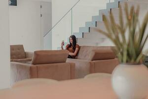 vrouw gebruik makend van smartphone voor video telefoontje terwijl zittend in modern huis foto