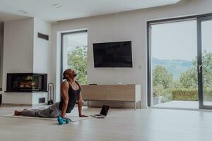 opleiding Bij huis. sportief Mens aan het doen opleiding terwijl aan het kijken online zelfstudie Aan laptop, oefenen in leven kamer, vrij ruimte foto