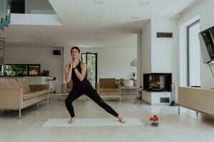 jong mooi vrouw sporten, uitrekken en beoefenen yoga met trainer via video telefoontje conferentie in helder zonnig huis. gezond levensstijl, welzijn en opmerkzaamheid concept. foto