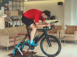 een Mens rijden een triatlon fiets Aan een machine simulatie in een modern leven kamer. opleiding gedurende pandemisch conditie. foto