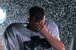 Amerikaans Amerikaans voetbal veld- eenzaam atleet krijger staand Aan een veld- houdt zijn helm en klaar naar Speel. speler voorbereidingen treffen naar rennen, aanval en partituur touchdown. regenachtig nacht met dramatisch mist, blauw licht foto