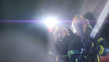 brandweerlieden gebruik makend van een water slang naar elimineren een brand gevaar. team van vrouw en mannetje brandweer in gevaarlijk redden missie. foto