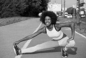 portret van sportieve jonge Afro-Amerikaanse vrouw die zich buiten uitstrekt foto