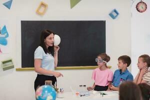 elementair school- wetenschap klas enthousiast leraar legt uit chemie naar verschillend groep van kinderen, weinig jongen mengsels Chemicaliën in bekers. kinderen leren met interesseren foto