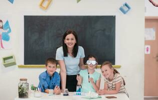 elementair school- wetenschap klas enthousiast leraar legt uit chemie naar verschillend groep van kinderen, weinig jongen mengsels Chemicaliën in bekers. kinderen leren met interesseren foto