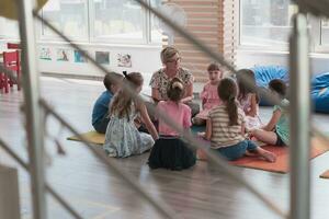 lezing tijd in elementair school- of kleuterschool, leraar lezing een boek naar kinderen in elementair school- of kindergaden. selectief focus foto