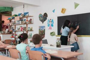 elementair school. de vrouw leraar helpen de kind leerling terwijl schrijven de antwoord Aan de schoolbord. foto