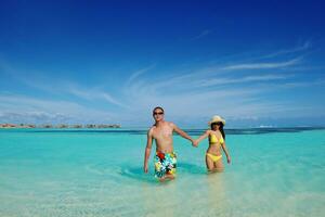 gelukkig jong paar genieten van zomer Aan strand foto