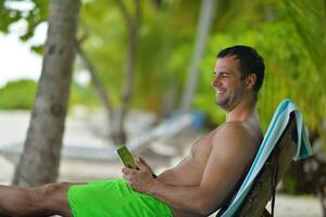 Mens ralaxing en gebruik tablet Bij strand foto