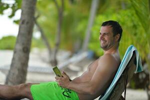 Mens ralaxing en gebruik tablet Bij strand foto