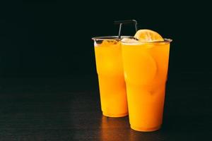 foto van twee sinaasappellimonades op donkere tafel op zwarte achtergrond