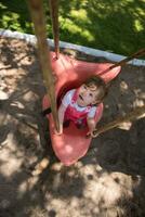 weinig meisje swinging Aan een speelplaats foto