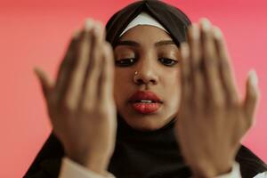 Afrikaanse moslim vrouw vervelend hijab en traditioneel moslim kleren poseren in voorkant van rood achtergrond foto