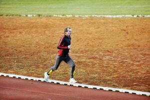 volwassen Mens rennen Aan atletiek bijhouden foto